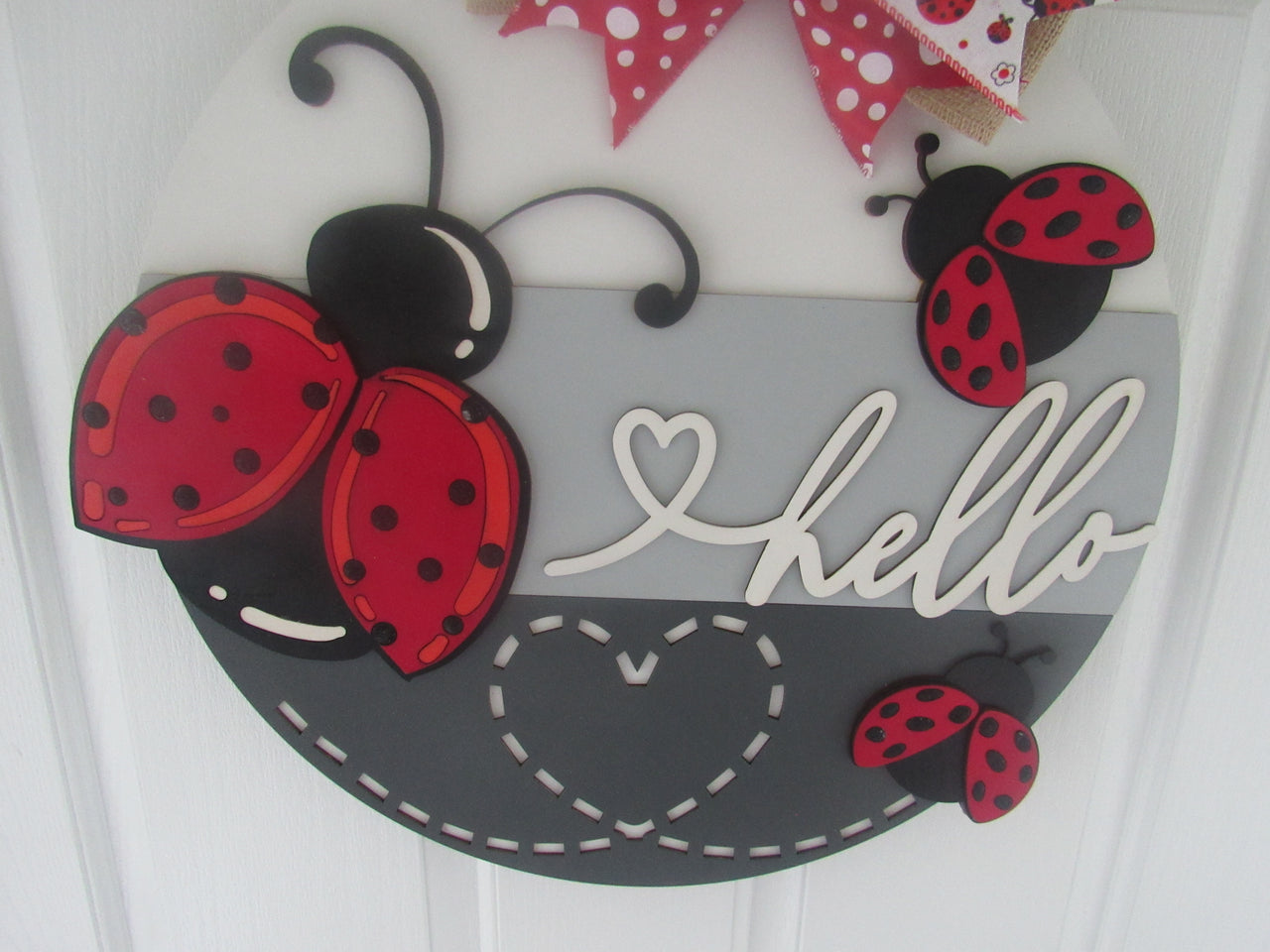 Cute ladybug door hanger with layered wood design, perfect for welcoming guests.