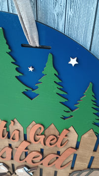 Thumbnail for Rustic cabin door hanger with marshmallows on sticks, fire pit, and Adirondack chairs.