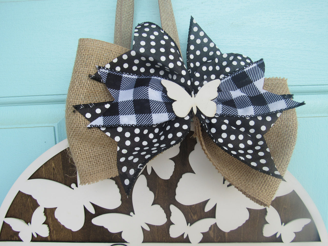 round wood welcome sign with white butterfly cutouts and bow