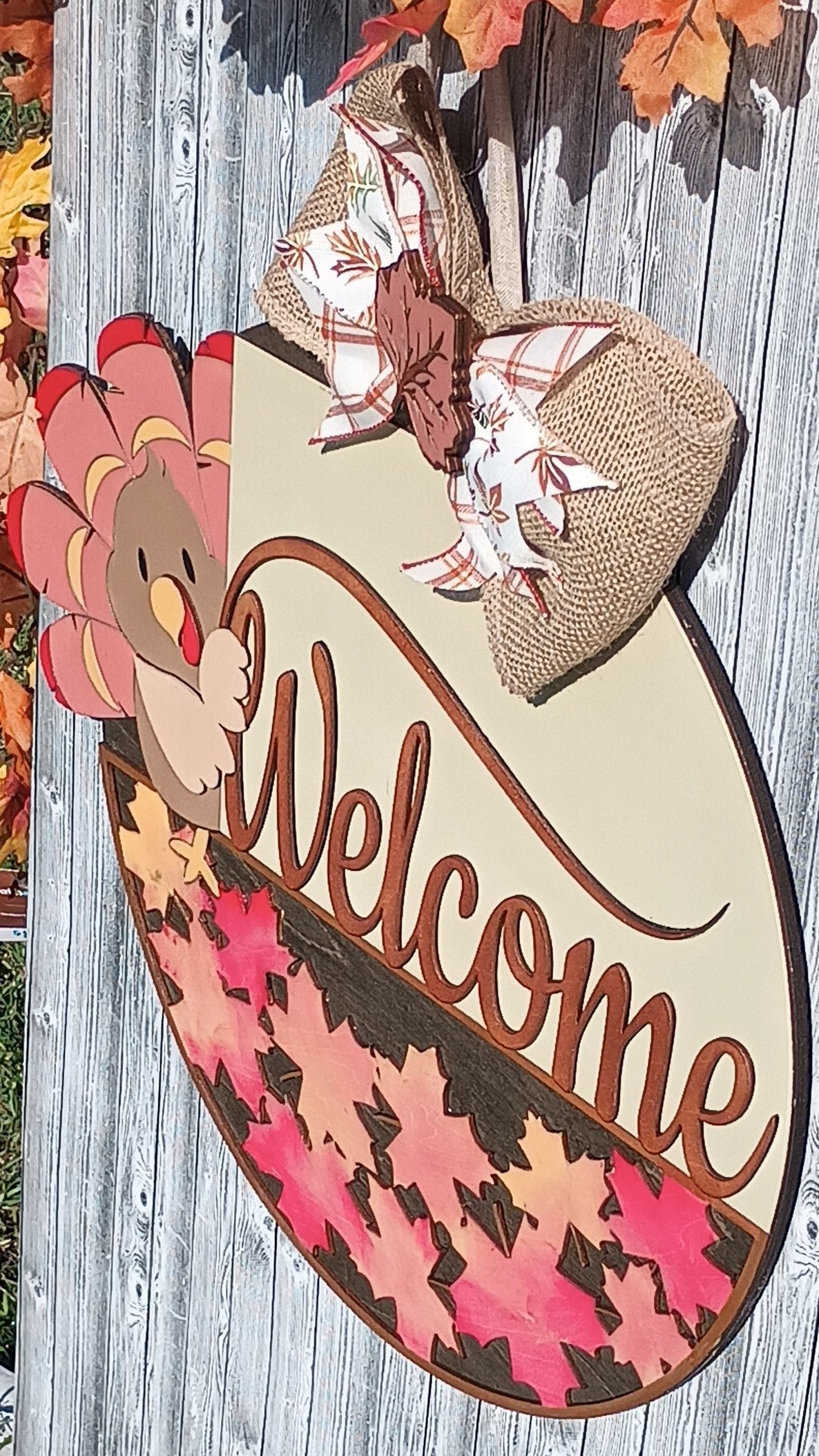 Round wooden door sign featuring a cute turkey and autumn leaves with welcome text