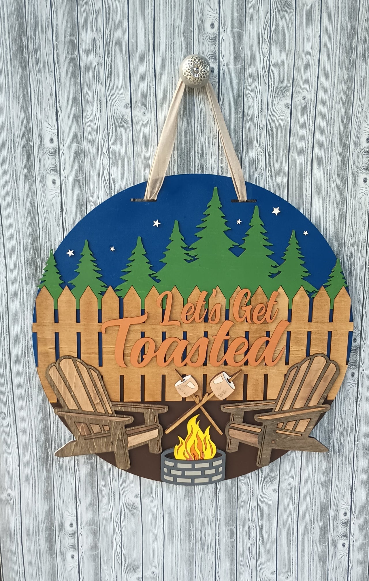 Handcrafted wooden camping sign with "Let's Get Toasted" text and rustic outdoor scene.