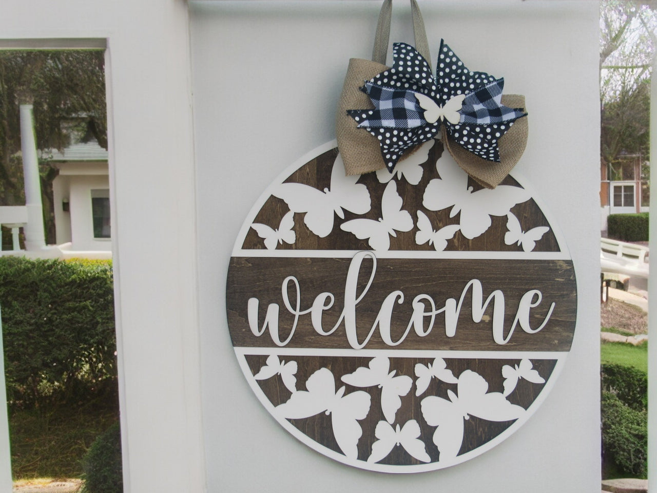 Wooden welcome sign with butterfly motif and black and white bow
