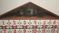 Top decorative detail of a wooden advent calendar, showcasing festive trees and reindeer silhouette design.