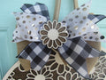 Charming summer door hanger with white daisy design, checkered ribbon bow, and welcome message on a round wooden base.