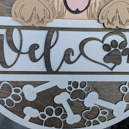 Decorative sign with paw prints, bones, and the word 'Welcome' on a wooden background.