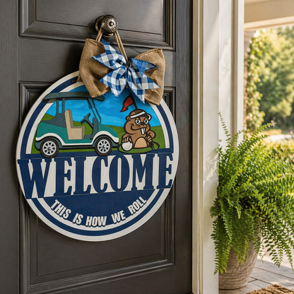 Decorative door sign with a cartoon gopher and golf cart, featuring the text 'Welcome, This is How We Roll', on a dark wooden door.