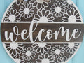 Handmade wooden daisy wall decor with floral cutouts, elegant welcome text, and checkered bow for summer decorating.