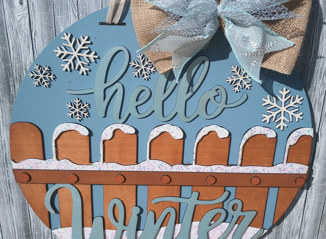 Hello Winter wooden door hanger with hand-painted details, glitter accents, and a handcrafted bow, perfect for winter door decorations.