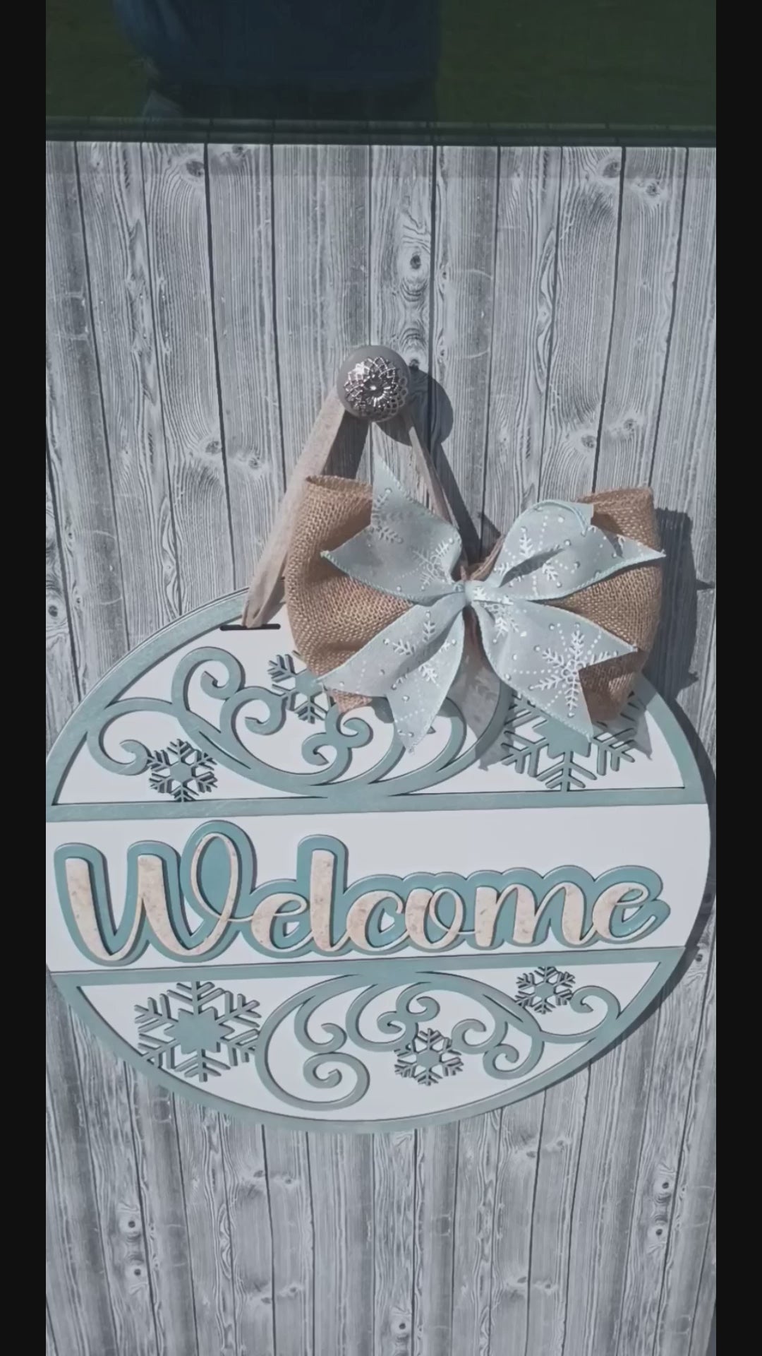 Close-up video showcasing the 18-inch Welcome Winter door hanger with hand-painted snowflake accents, burlap bow charm, frosty swirl details, and protective bumpers, perfect for winter front door decor