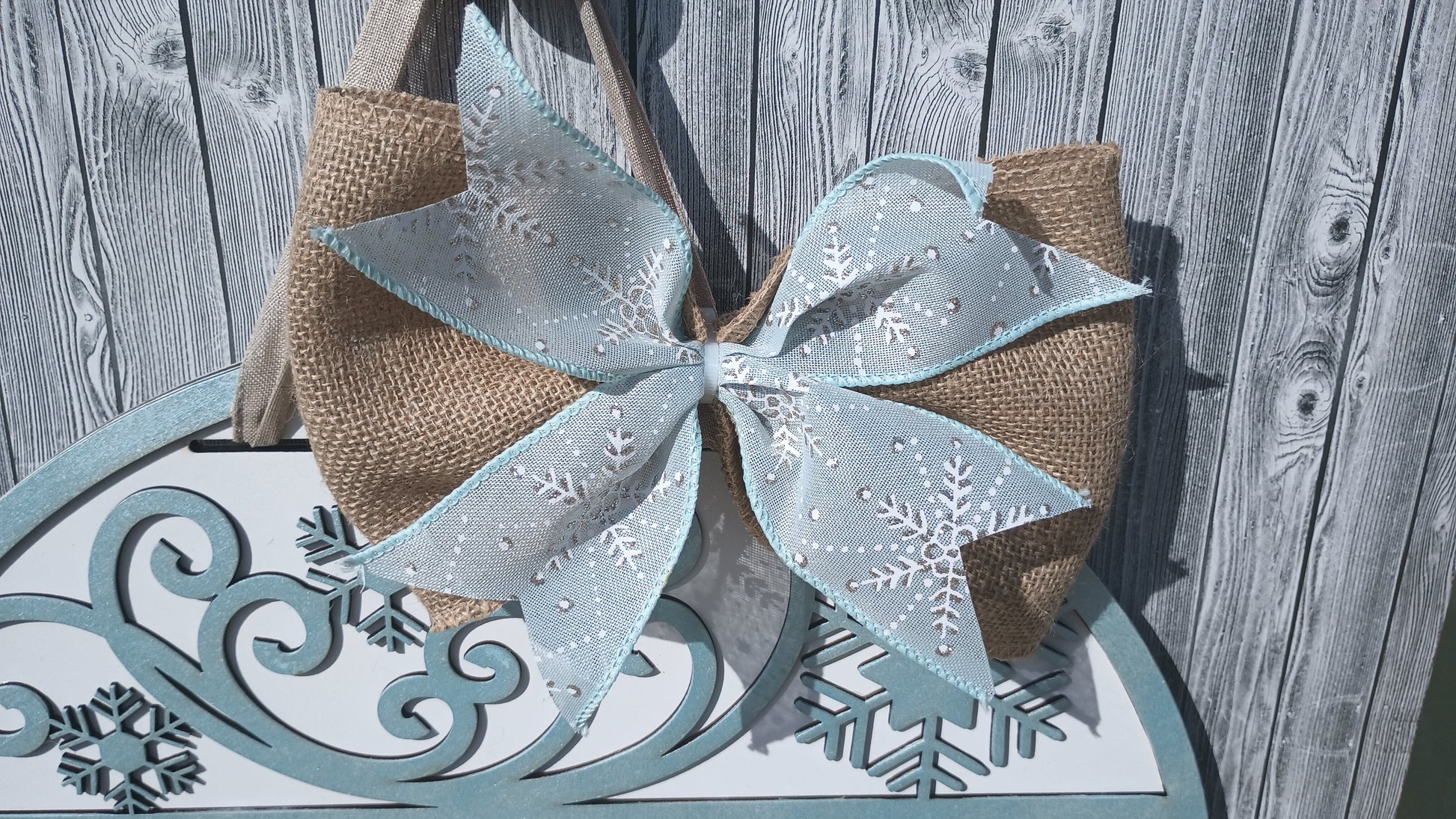 Handcrafted Welcome Winter door sign with rustic burlap bow and frosted snowflake patterns for seasonal home entry decor.