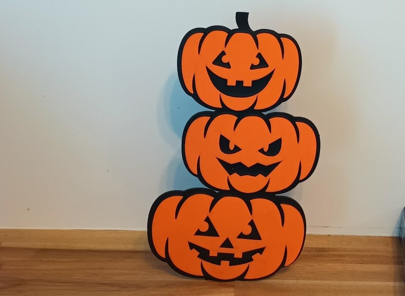 Trio of stacked jack-o'-lanterns in orange and black
