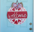 Hand-painted Valentine door hanger with bold red and pink hearts, 18-inch round wooden heart door decor, featuring a layered bow with heart charm.