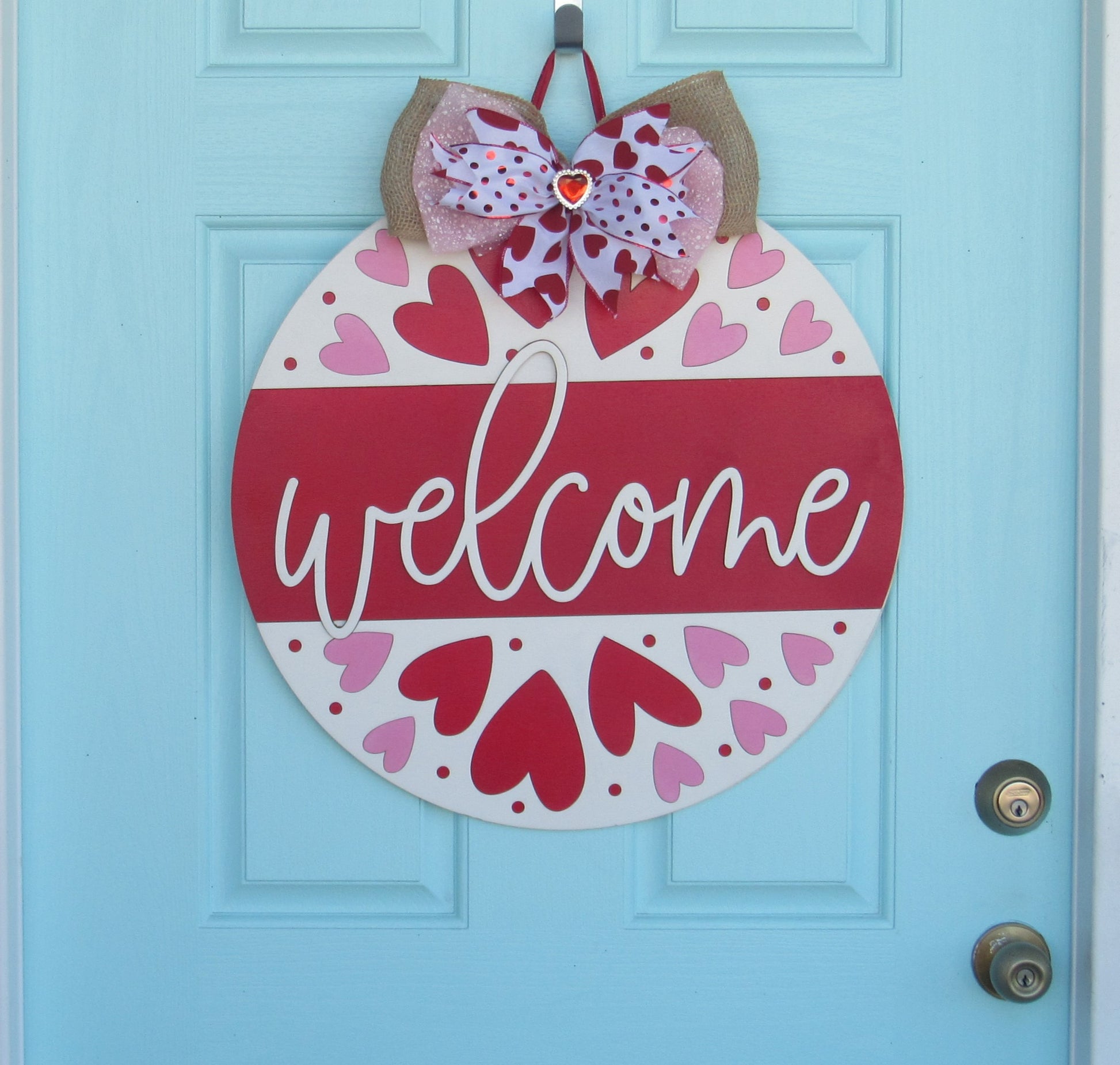 Hand-painted Valentine door hanger with bold red and pink hearts, 18-inch round wooden heart door decor, featuring a layered bow with heart charm.