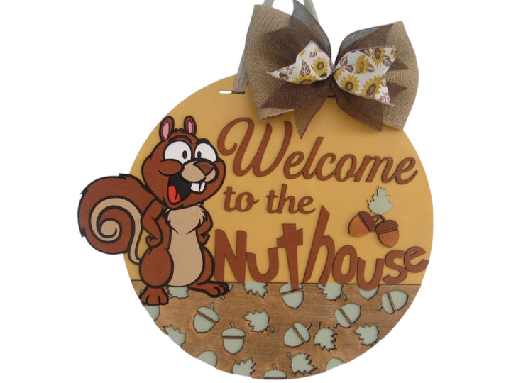 Cute cartoon squirrel welcome sign with “Welcome to the Nuthouse” text and acorn accents, perfect for front door decor.