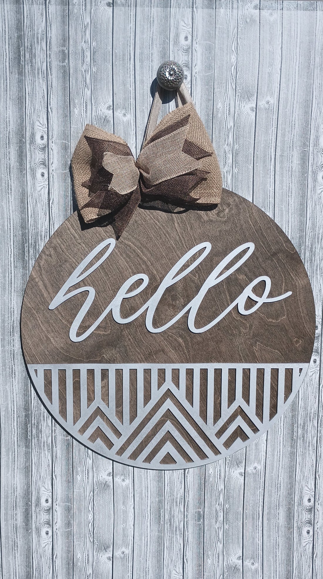 Stylish wooden door sign with "hello" script and geometric cutout, accented with a rustic burlap bow.