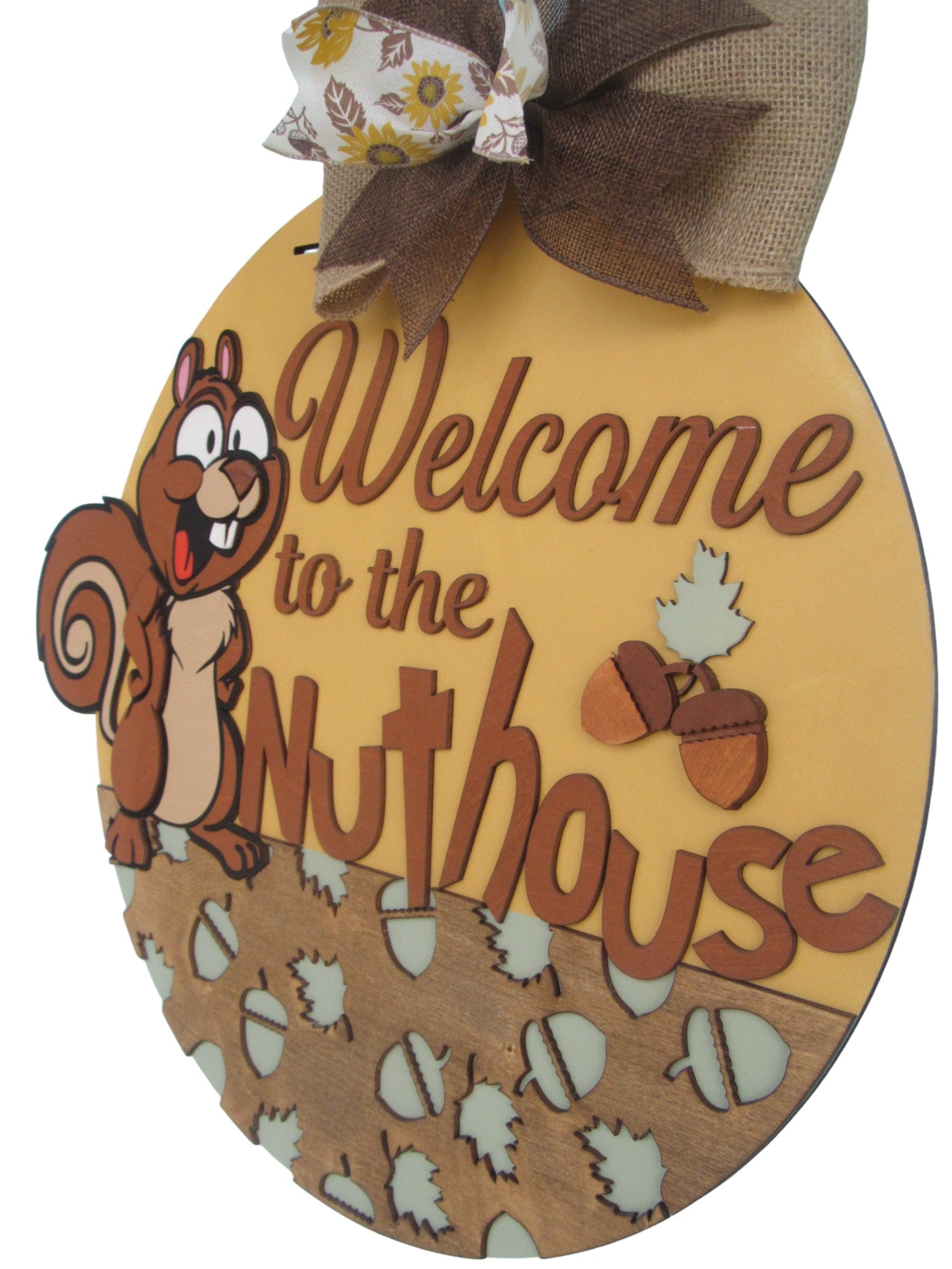 Humorous round welcome sign with nut and leaf cutouts, accented by a sunflower ribbon for seasonal charm.

