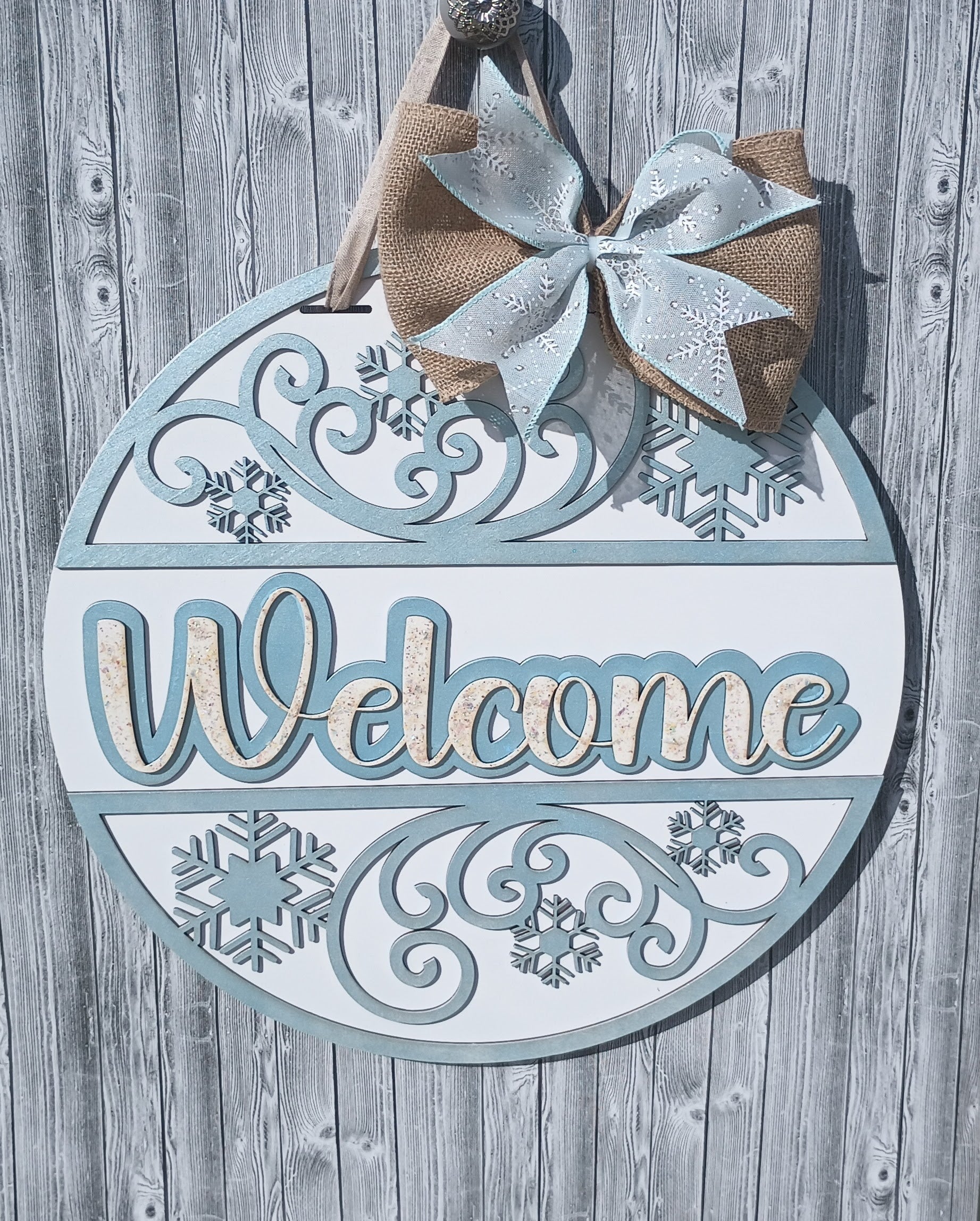 Handcrafted Welcome Winter door sign with burlap bow and frosted snowflake patterns for seasonal home entry decor.