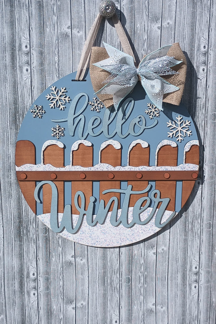 Winter door hanger with glittery Hello Winter text, hand-painted snow accents, and protective bumpers, ideal for winter front door decorations.
